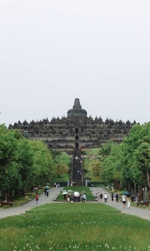 People visiting the iconic Borobudur Temple in Central Java, Indonesia, on a cloudy day.